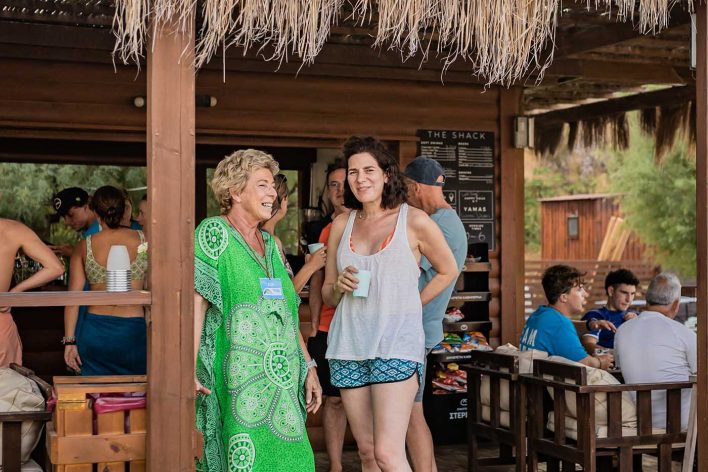 Two woman stand chatting at a beach bar