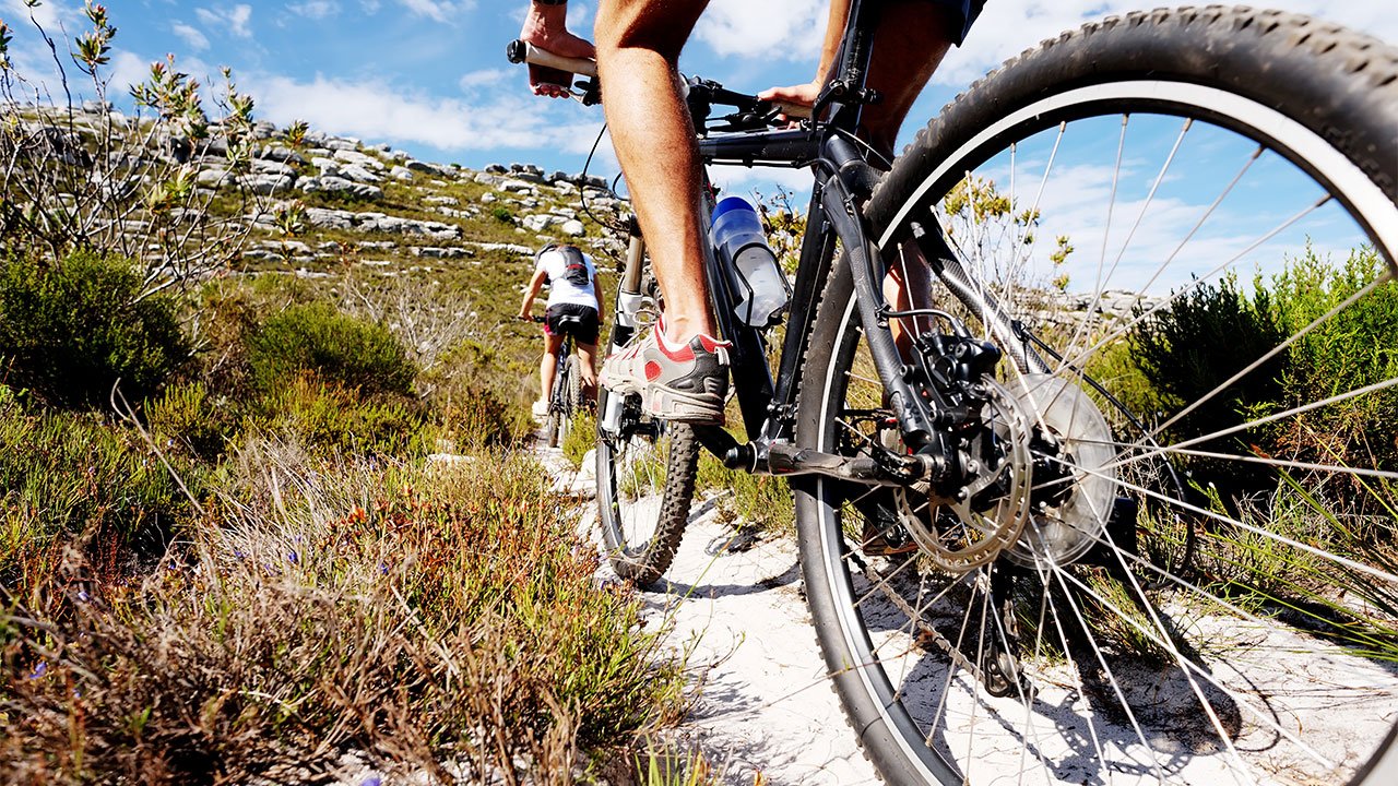 two mountain bikes ride along a stone trail in the countryside