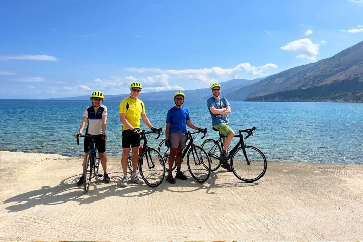 4 people stand with their road bikes by the sea