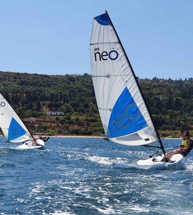 two sailing dinghies sail towards the camera. They are RS NEO dinghies with blue and white sails