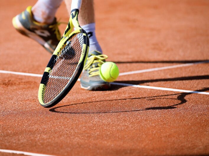 Clay tennis court and player with racket and ball