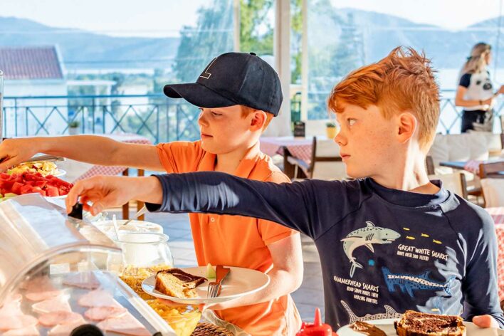two children help themselves to a buffet breakfast