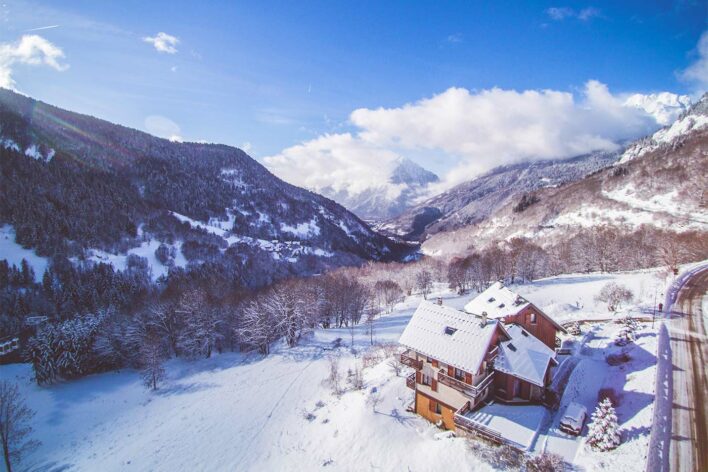 Aerial view of snow covered ski chalet with snow covered hillside behind it