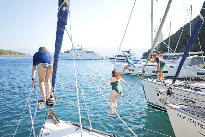 girls jumping off a yacht as part of a flotilla in Greece