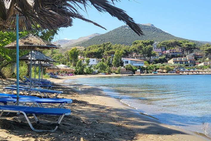 Sun loungers on a beach beside the sea with view towards Beach Club Hotel