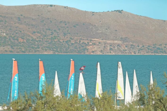 Sea view with the tops sailing dinghy sails and also a person wing surfing on the sea