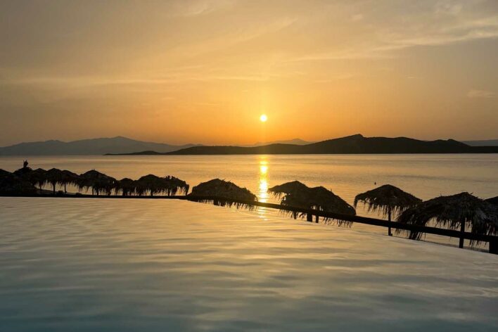 Sunset view of infinity pool with sea behind it