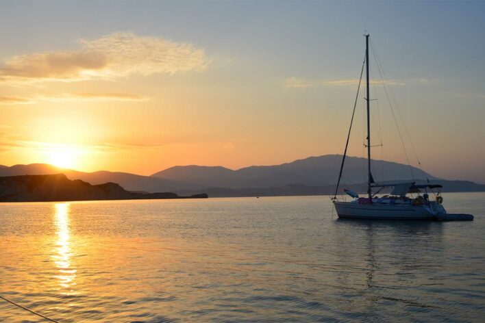 Sailing yacht moored at anchor on the sea with a sunset at the background